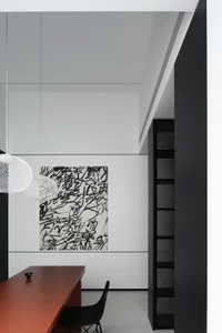 A minimalist office space with a black and white color scheme featuring metallic elements like the pendant light and the chai