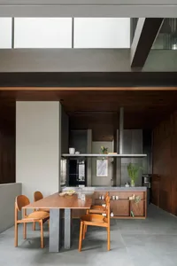 A modern living room with concrete walls, a wooden dining table, and a minimalist design.