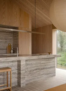 Modern kitchen with marble countertops and wooden stools.