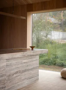 A modern interior design featuring a stone countertop with a woven rope decoration and a wooden bowl on top, framed by a larg