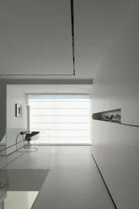 A minimalist white interior space with glass elements and a large window.