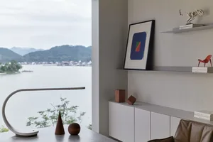 A casual office space featuring mixed materials and a serene waterfront view.