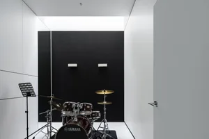 A minimalist music room with a black acoustic foam wall and a Yamaha drum set.