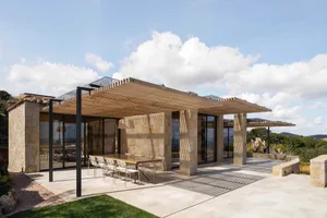 Modern residential property with wooden pergola, stone walls, and tiled patio area.