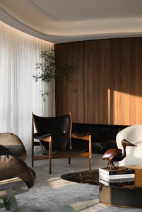 A modern living room featuring a marble coffee table, black accent chair, and wooden wall.