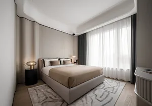 Modern minimalist bedroom featuring fabric bedding on a wooden platform bed under large windows with sheer curtains.