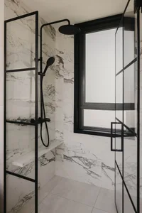 A minimalist bathroom with a marble shower area, black fixtures, and a window.