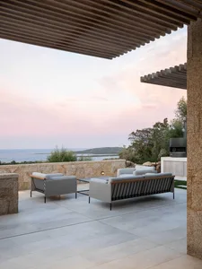 Modern residential outdoor lounge featuring granite, wood, and concrete with a scenic ocean view.