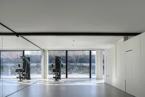 Modern minimalist fitness center with metal windows and exercise equipment.