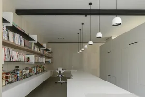 A modern minimalist office with white materials and a sleek, white desk.