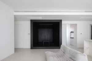 A modern minimalist living room with a black box feature wall, concrete floor, and white sofa.