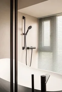 Minimalist bathroom with metallic fixtures and a white bathtub, featuring a shower head and controls.