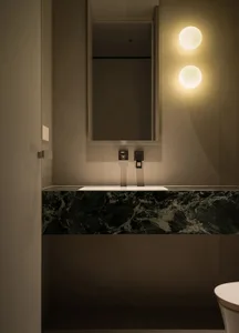 Modern bathroom with sleek marble countertop, illuminated by two spherical lights, and a minimalist design.