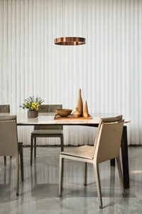 Modern dining room featuring a marble table with minimalist chairs, vase, and tray arrangement.