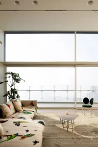 A modern living room featuring a printed sofa with floral designs, round tables, and a potted plant.