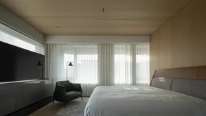 Modern bedroom with white curtains, wooden walls, and a large window