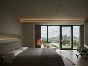 Spacious bedroom with hardwood flooring, large windows, and a view of the city.