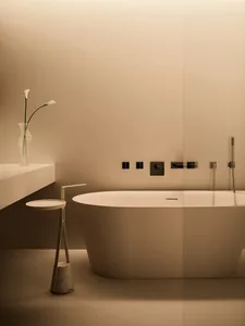 Minimalist bathroom with a concrete bathtub and vase of white flowers