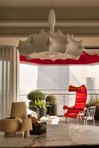 Modern living room with marble table, concrete floor, potted plants, and red armchair.