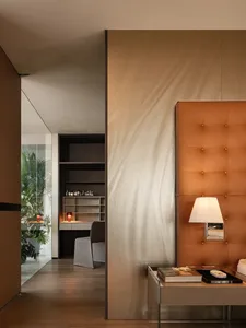 Modern bedroom interior with a brown leather upholstered headboard, wooden flooring, and a glass partition.