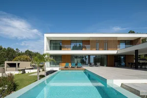 Modern residential house with concrete and wooden exterior features a large swimming pool.