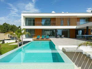Modern minimalist pool house exterior with white facade, large windows, wooden accents, and a rectangular swimming pool.