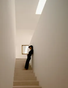 簡約室內設計，搭配石材樓梯，畫面中有人倚靠在牆上。