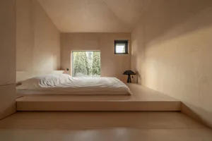 Minimalist bedroom with wood platform bed, white bedding, and small windows