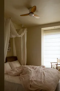 A minimalist bedroom with bluish fabric curtains and a comfortable-looking bed.