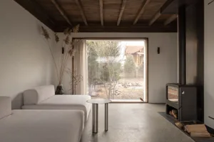A minimalist living room with concrete elements, including a concrete floor and furniture. Large window provides natural ligh