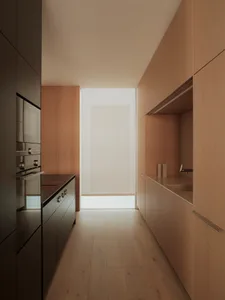 Modern minimalist kitchen with hardwood floors and wooden cabinetry.
