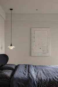 Minimalist bedroom featuring dark bedding with a patterned textile design.