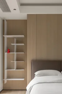 Minimalist bedroom featuring a brown wooden wall panel, a white bed with white pillows, and a white shelf system.
