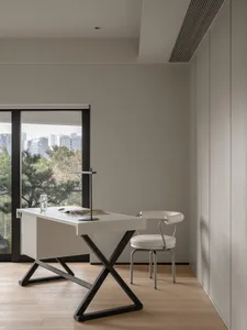 Modern home office space with sleek, minimalist desk, chair, and floor-to-ceiling windows overlooking a cityscape.