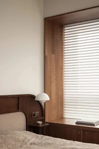 A modern bedroom featuring wooden cabinets and a window seat with blinds.