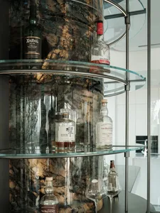 Glass shelves and bottles on a curved bar counter with a marble background.