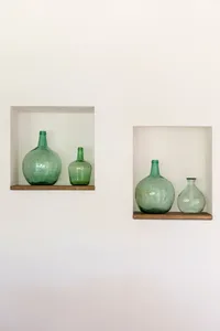 A pair of shelves with green glass bottles arranged in green glass bottles.