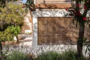 Modern sliding door with a wooden lattice and lavender plants in front of a house with a wooden roof.