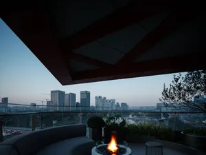 Modern terrace featuring glass walls overlooking a busy cityscape at dusk