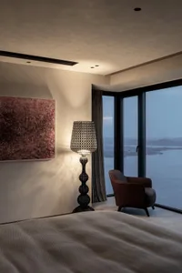 A modern bedroom featuring a tall, metal floor lamp emitting warm light in a contemporary interior setting.