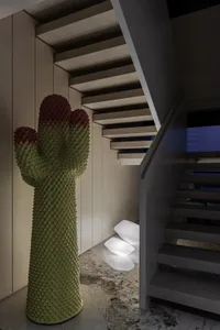 Modern staircase design featuring a realistic cactus sculpture with red flowers and illuminated lighting.