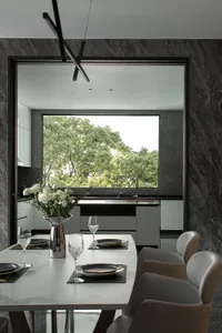 A modern kitchen with a white marble countertop and floor, featuring sleek cabinets and a large window with a view of green t