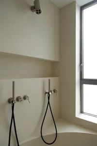 Modern, minimalist bathroom with concrete walls and a window.