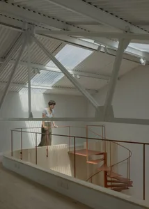 A person standing near a modern, minimalist interior with a spiral staircase made of metal.