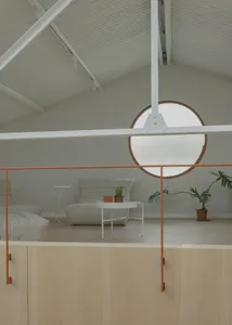 A minimalist living space featuring wood flooring, white furniture, and a circular window.