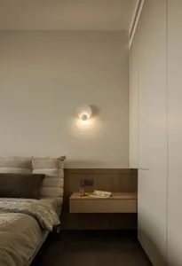 A modern minimalist bedroom with a single bed adorned with a beige textured headboard and matching cover, accompanied by a fl