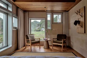 Modern living room with wooden furniture and a view of the mountains through large windows.