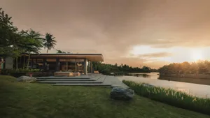 Modern house exterior featuring a glass wall and concrete patio.