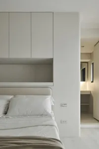 Modern minimalist bedroom featuring a neutral color palette and a neatly arranged bed with a headboard.