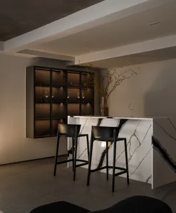A minimalist bar seating area with marble countertops and black stools.